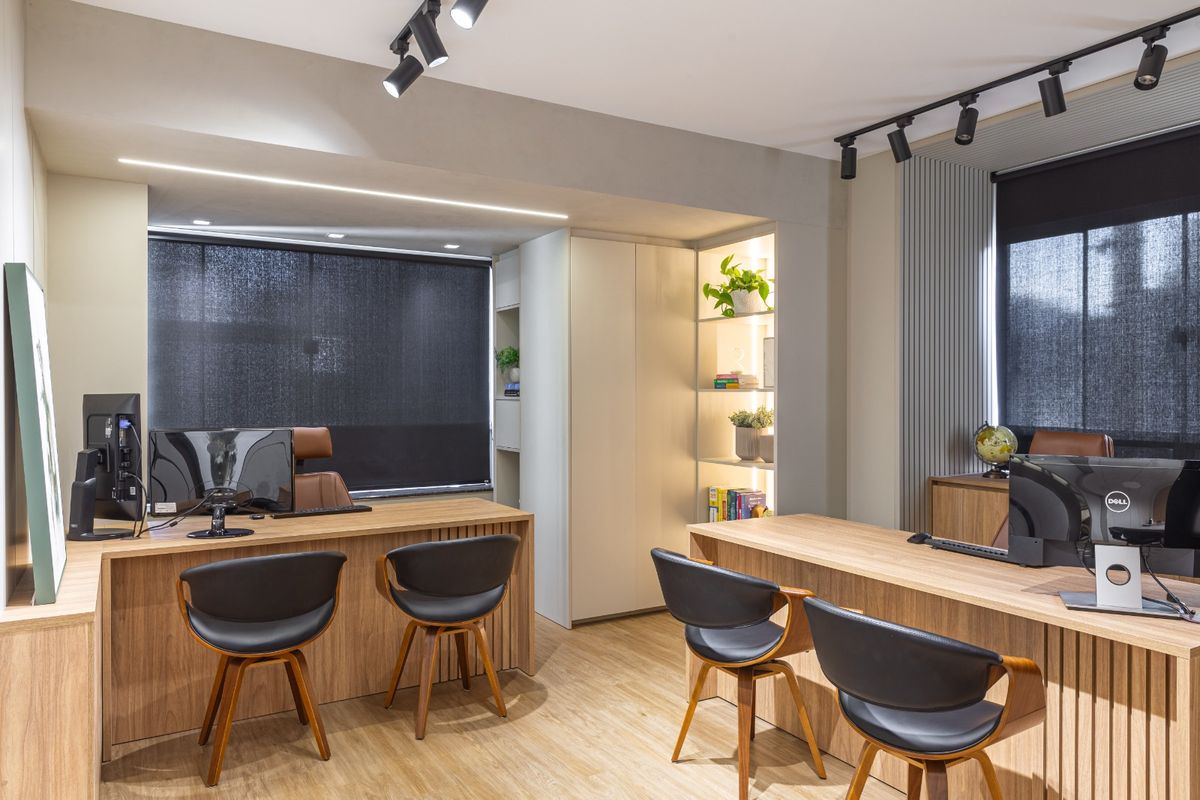Sala de atendimento com estações de trabalho e estante iluminada com livros e plantas